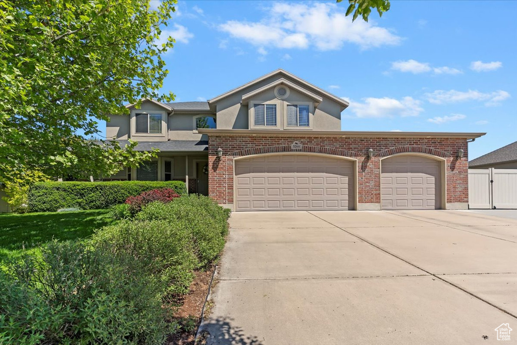 View of front of house featuring driveway, stucco siding, an attached garage, and brick siding