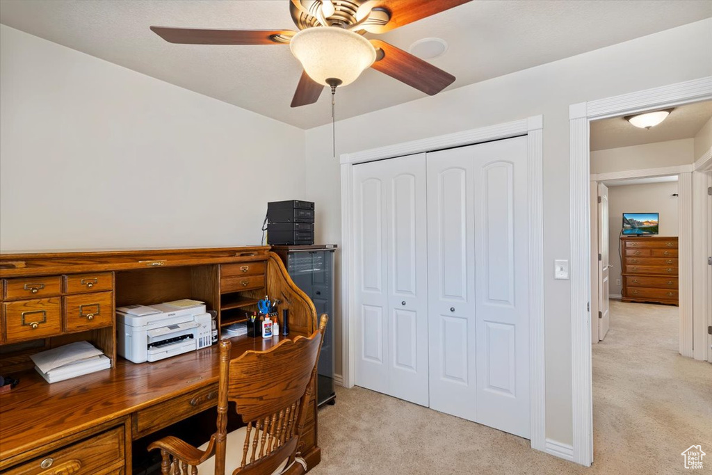Office space with light carpet, ceiling fan, and baseboards