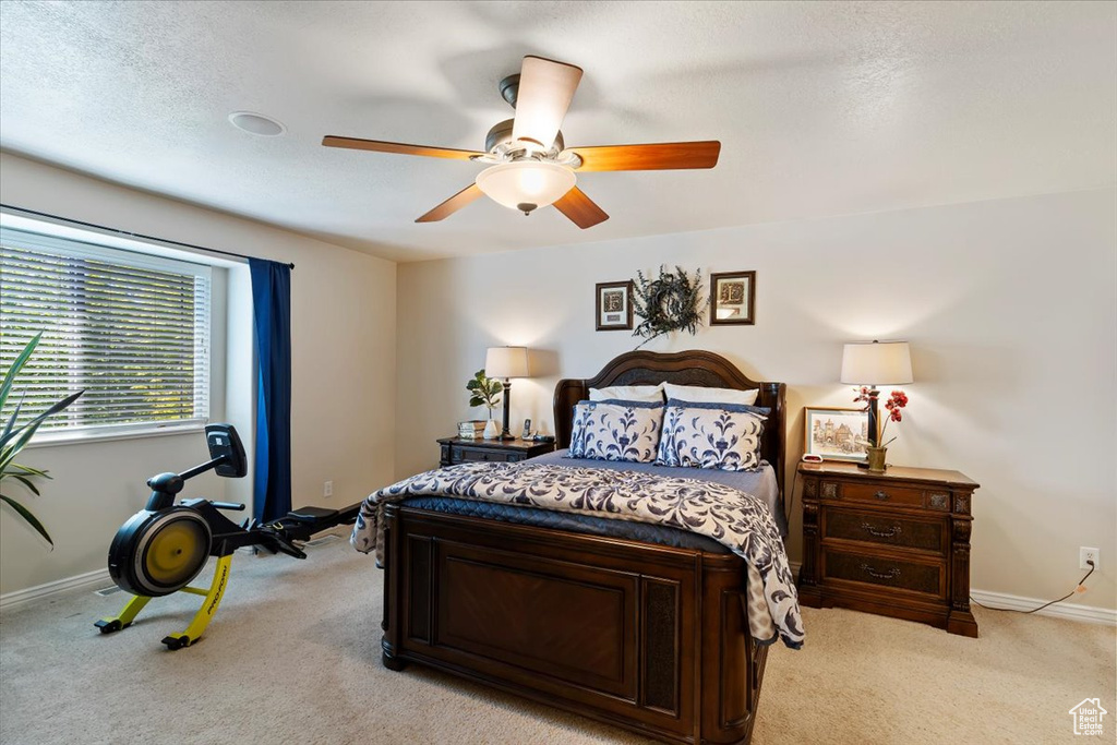 Bedroom featuring light colored carpet, baseboards, and a ceiling fan