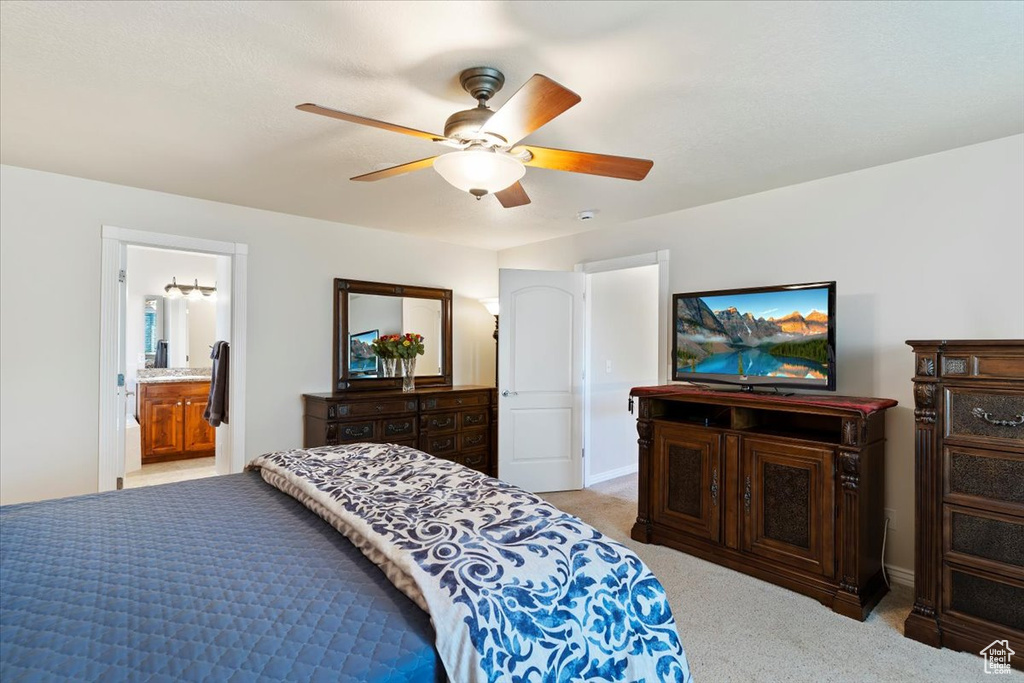 Bedroom featuring light colored carpet, ceiling fan, and ensuite bathroom