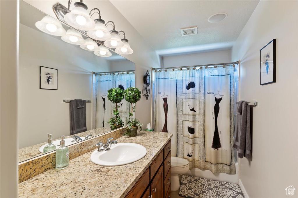 Bathroom with toilet, vanity, and a shower with shower curtain