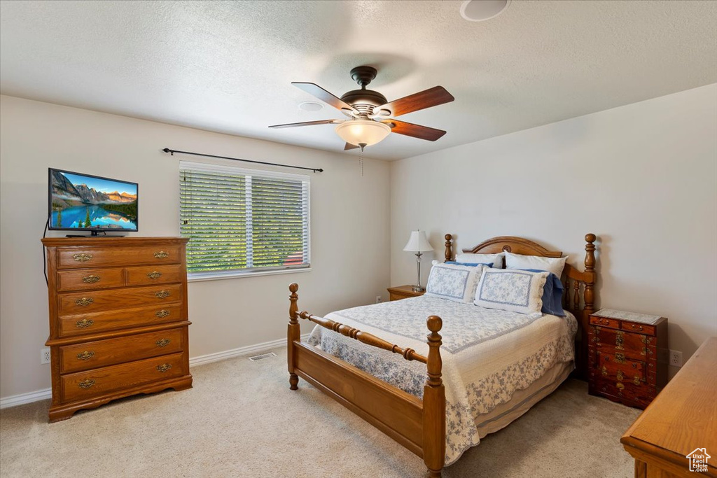 Bedroom with light colored carpet, baseboards, a ceiling fan, and a textured ceiling