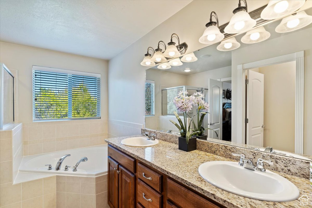 Bathroom featuring a bath, double vanity, and a stall shower