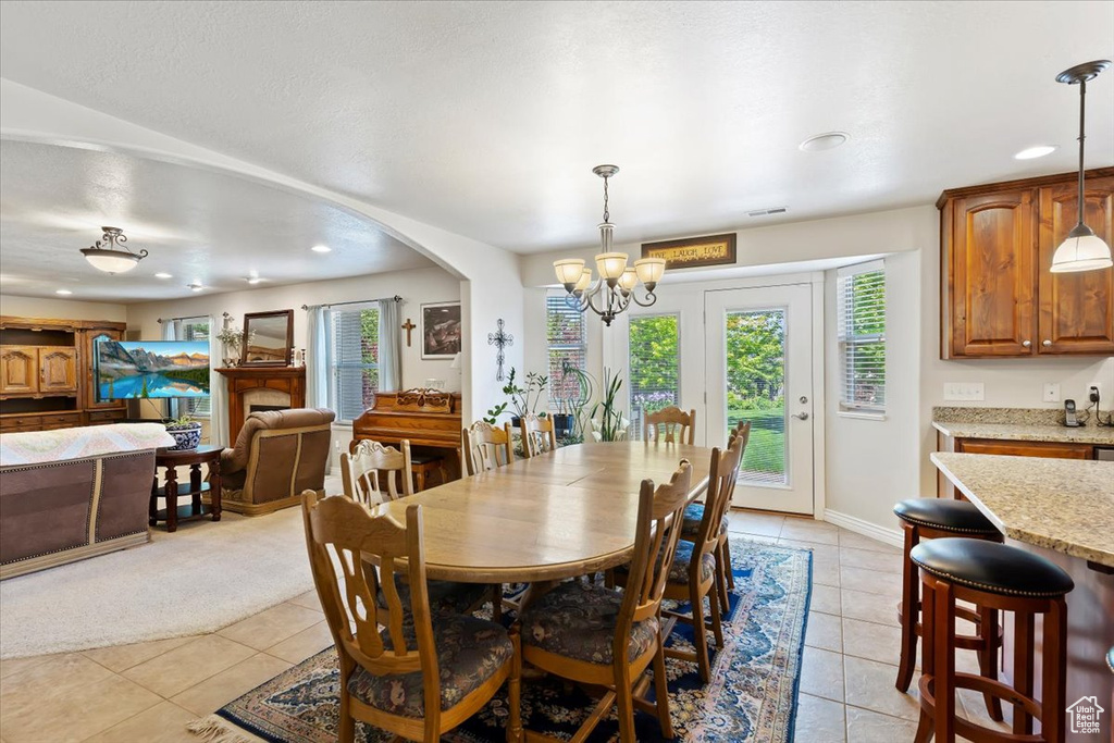 Dining room with light tile patterned floors, a chandelier, recessed lighting, baseboards, and arched walkways