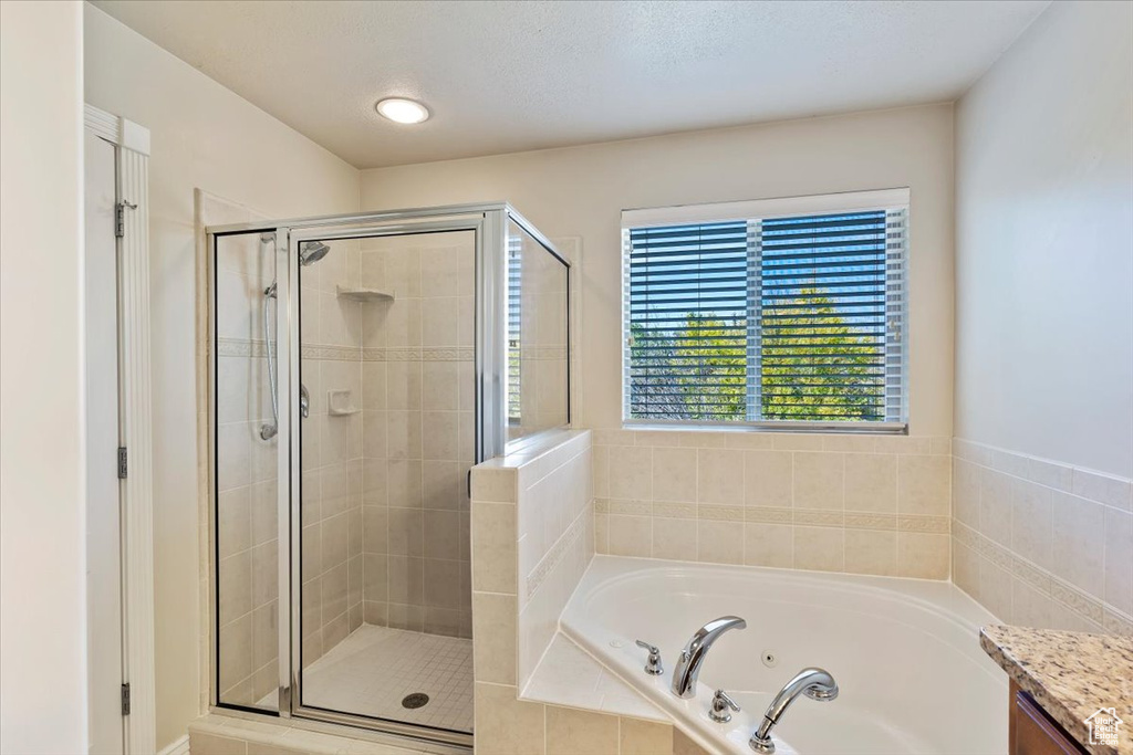 Bathroom featuring a stall shower and a tub with jets