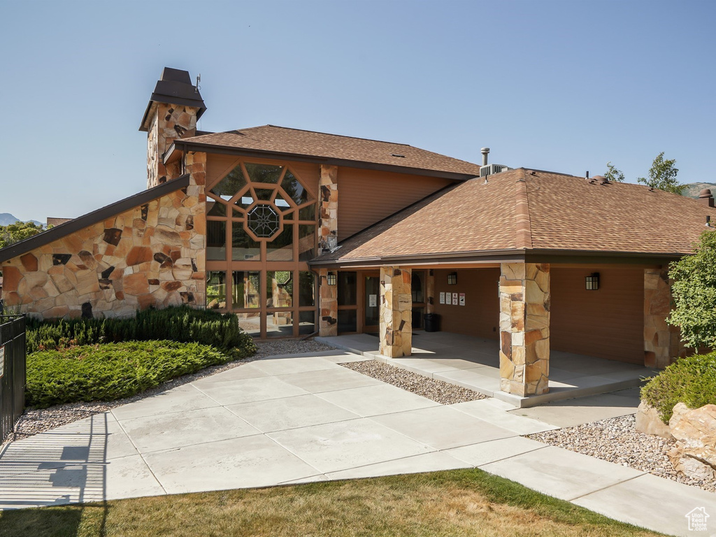 View of front of home with stone siding and a shingled roof