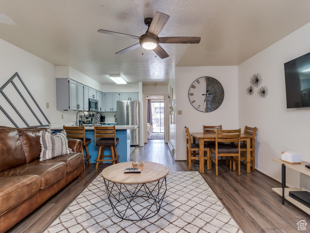 Living room with wood finished floors, a ceiling fan, and baseboards