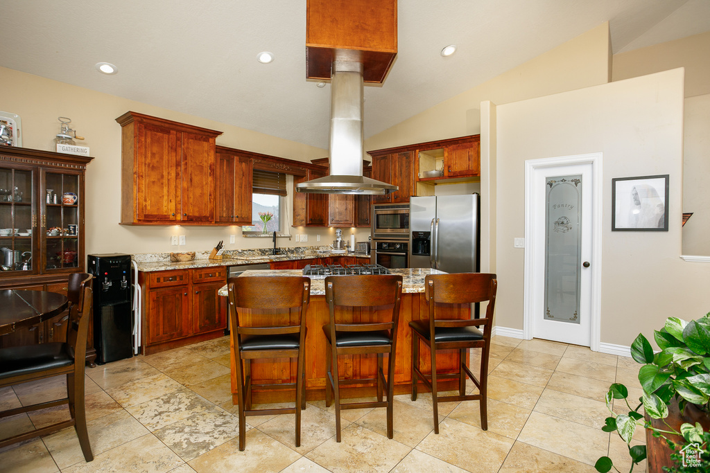 Kitchen with appliances with stainless steel finishes, a sink, a center island, vaulted ceiling, and baseboards
