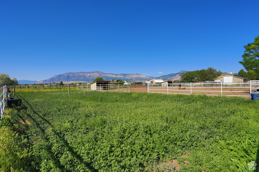 View of yard with an enclosed riding area, a mountain view, a rural view, and an outbuilding