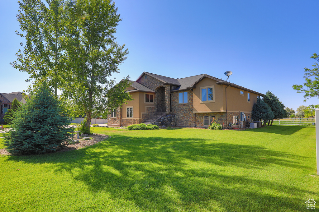 Back of house with stone siding, central AC, and stucco siding