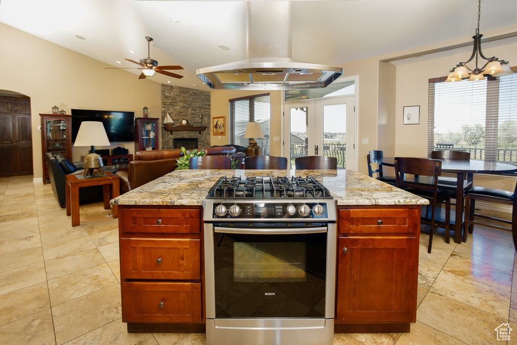 Kitchen featuring stainless steel range with gas cooktop, a ceiling fan, island exhaust hood, and light stone countertops