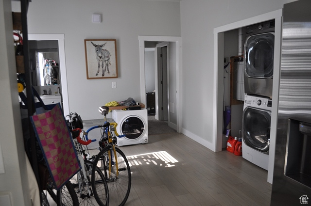 Washroom featuring stacked washer and clothes dryer, wood finished floors, and baseboards