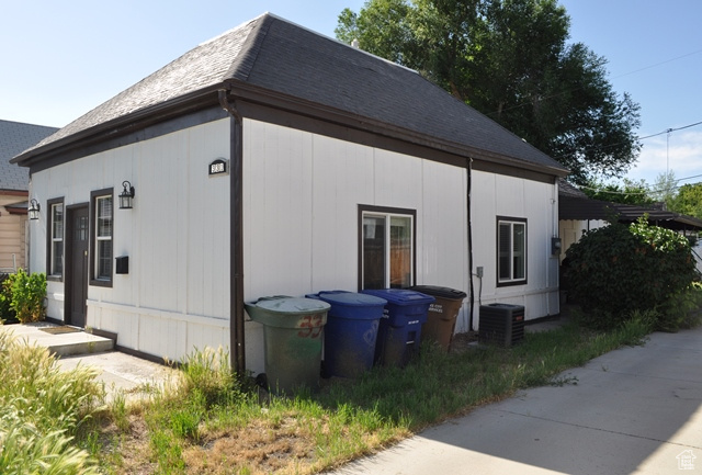 View of property exterior featuring cooling unit and a shingled roof