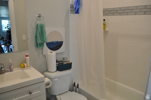Full bathroom featuring toilet, vanity, and shower / bath combination with curtain