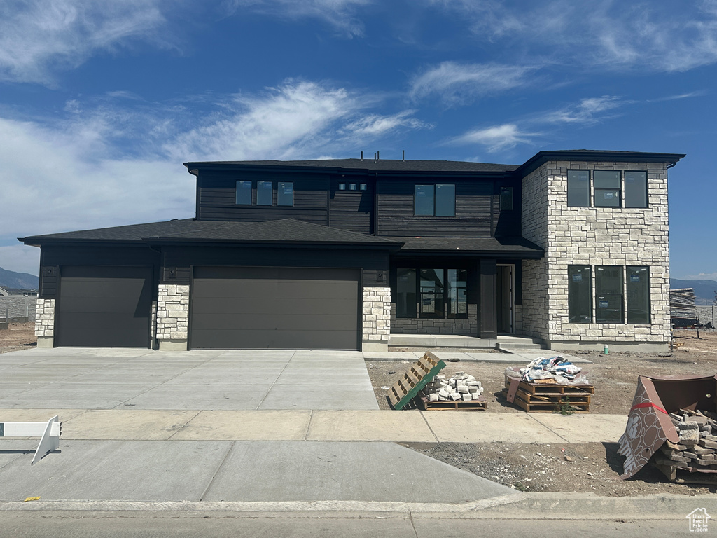 View of front of house featuring a garage, stone siding, and concrete driveway