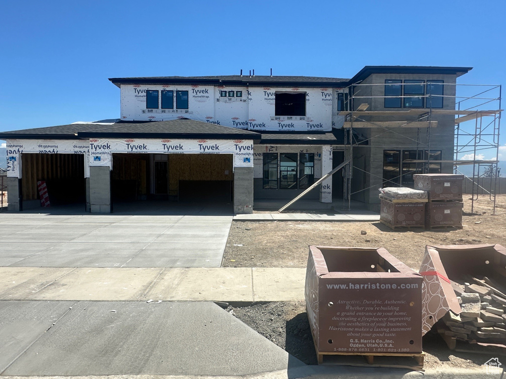 View of property featuring concrete driveway and a garage