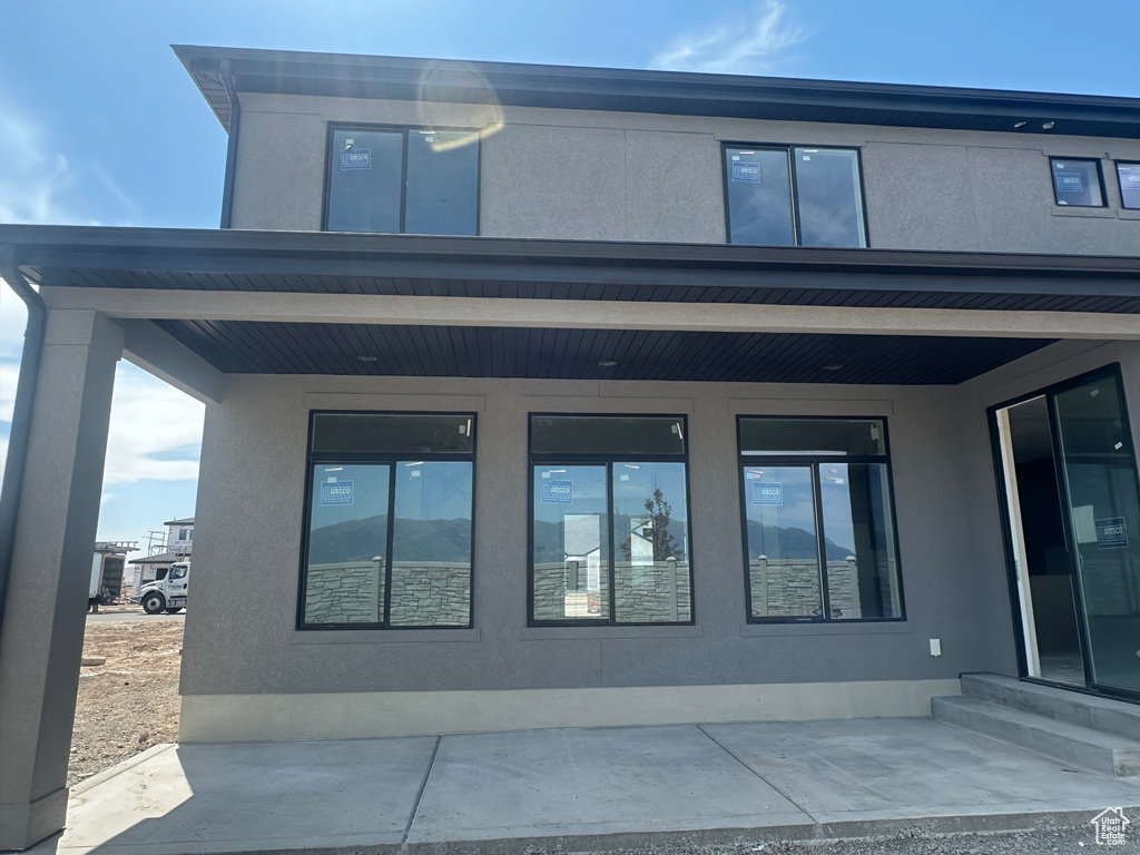Back of house with stucco siding and entry steps