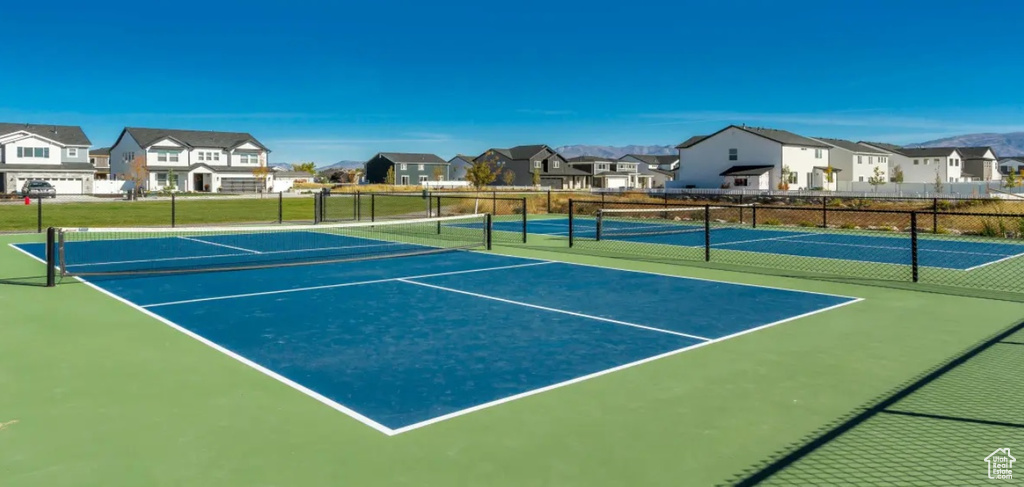 View of tennis court with a residential view