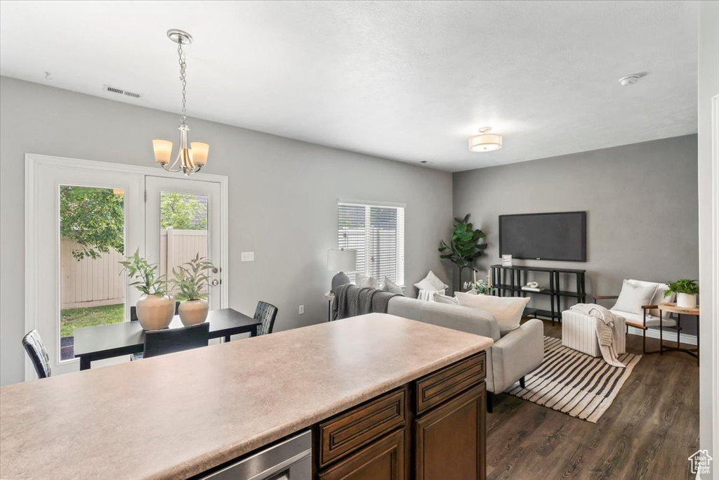 Kitchen featuring healthy amount of natural light, dark wood-type flooring, light countertops, and a chandelier