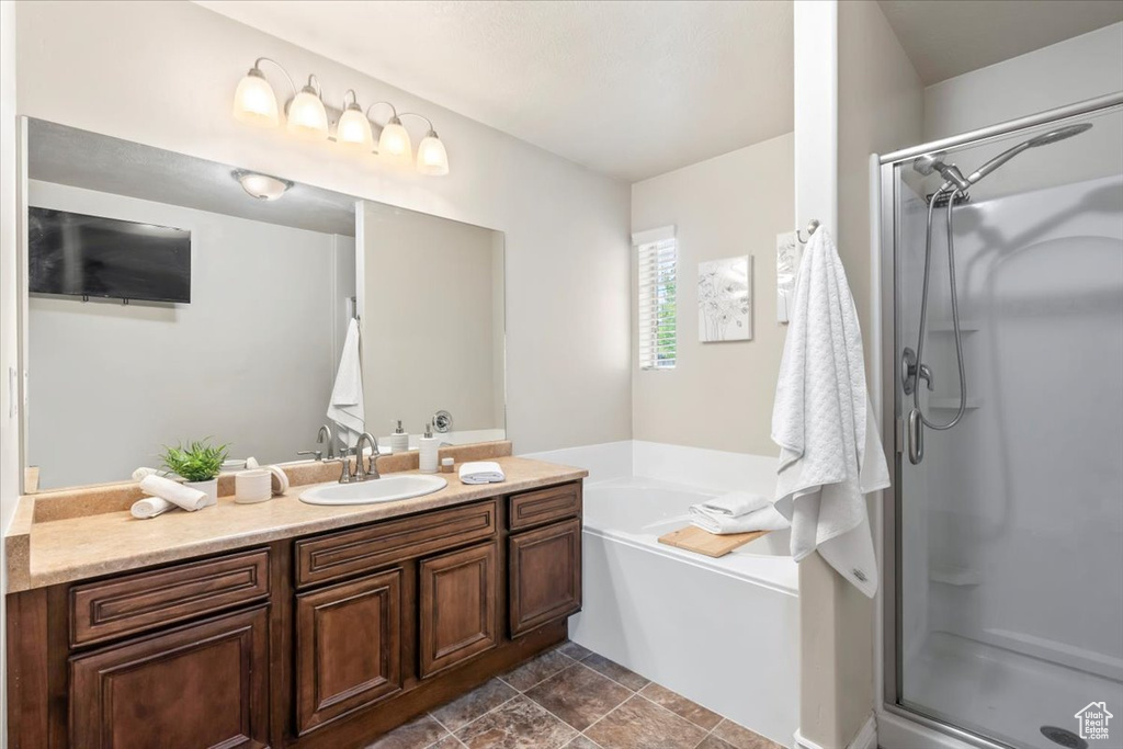 Bathroom featuring a stall shower, vanity, and a garden tub