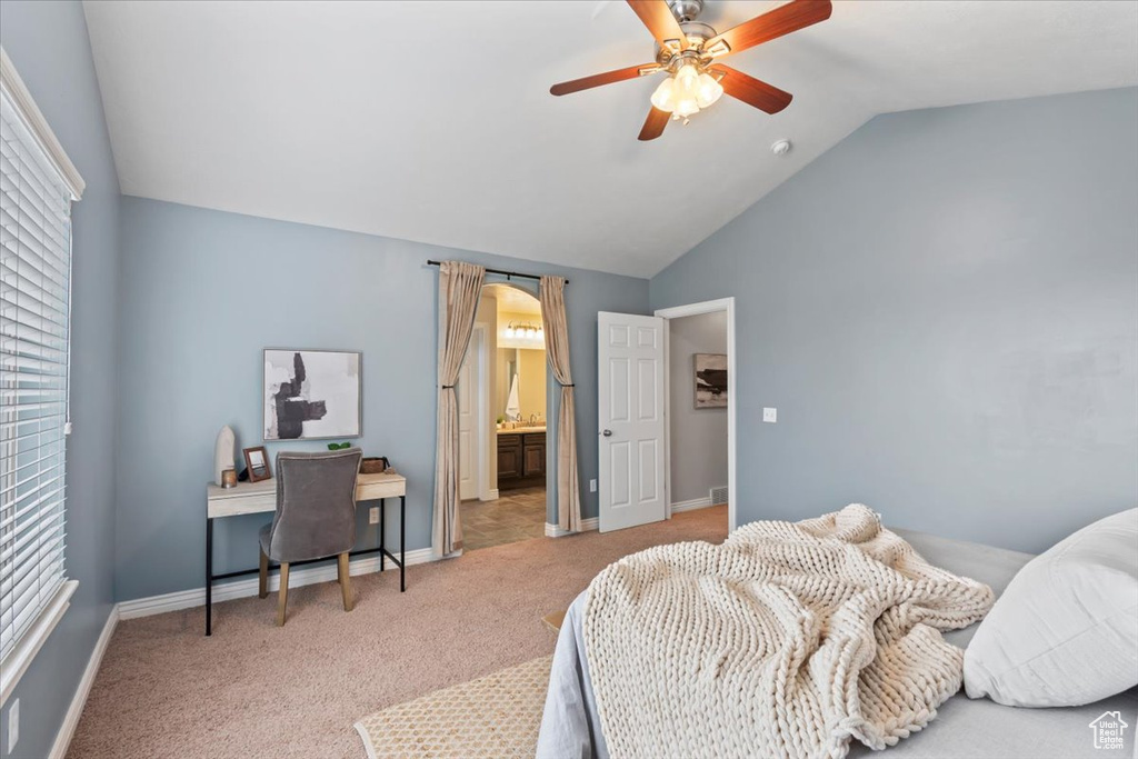 Carpeted bedroom featuring vaulted ceiling, a desk, baseboards, a ceiling fan, and connected bathroom