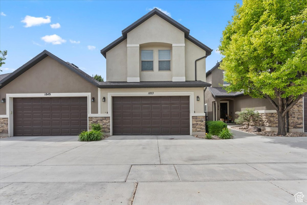 View of front of house with stucco siding, stone siding, and driveway
