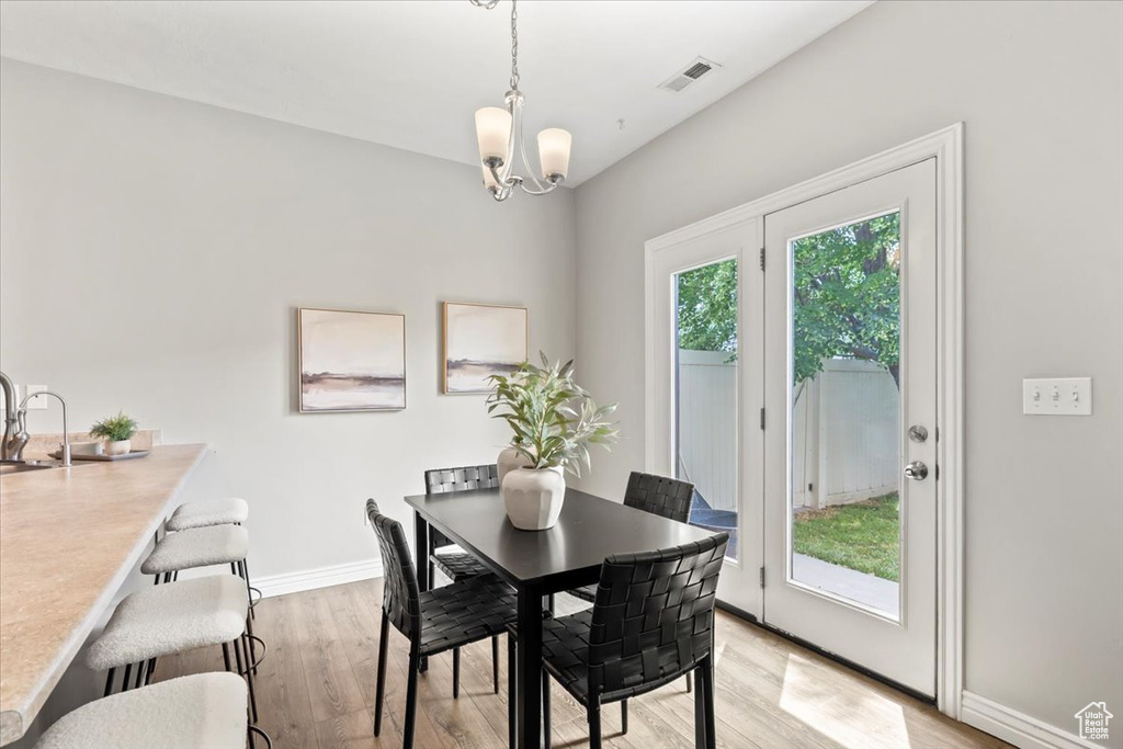 Dining room with a chandelier, light wood-style floors, and baseboards