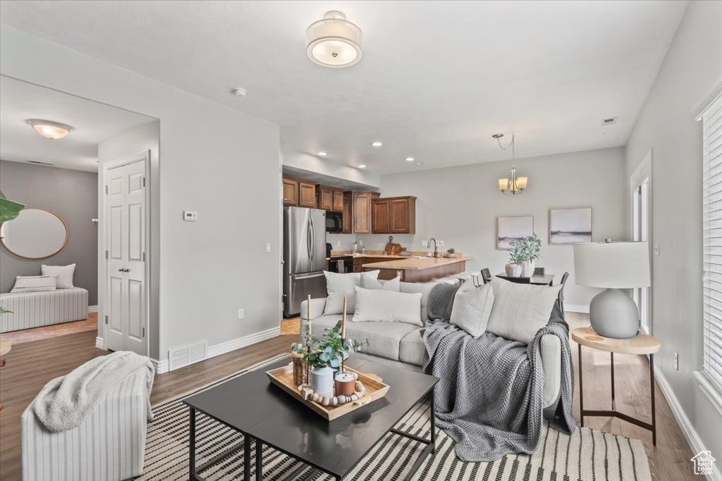 Living area with wood finished floors, baseboards, a chandelier, and recessed lighting