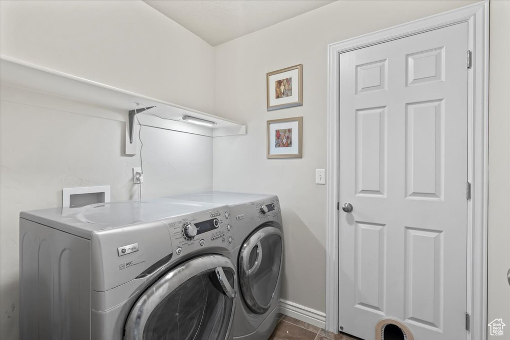 Washroom featuring washer and dryer, baseboards, and dark tile patterned floors