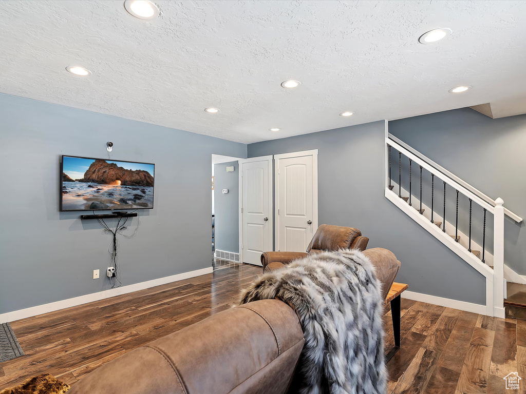 Living room with wood finished floors, recessed lighting, baseboards, stairway, and a textured ceiling