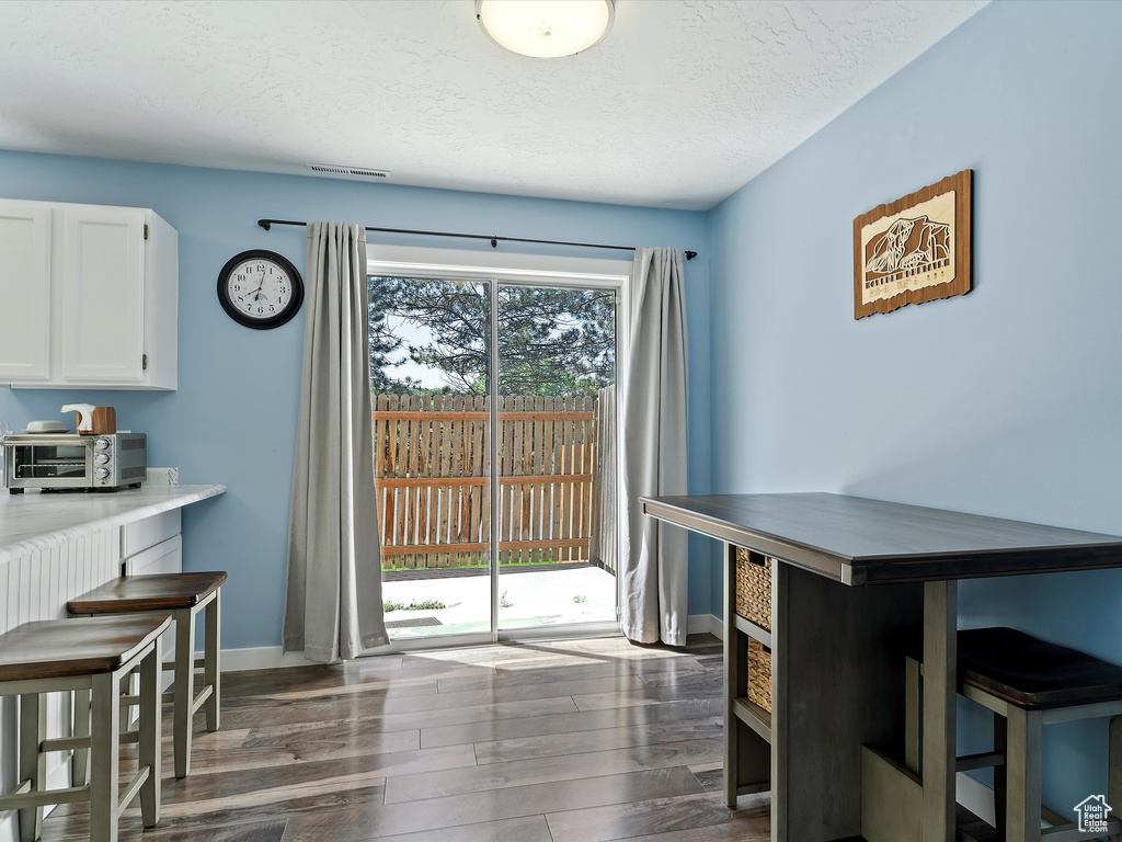 Dining space with wood finished floors, baseboards, and a textured ceiling