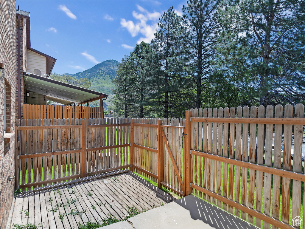 Wooden terrace featuring a mountain view, a fenced backyard, and a gate