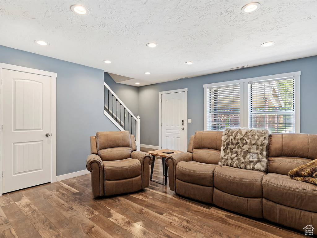 Living area featuring wood finished floors, recessed lighting, stairway, baseboards, and a textured ceiling