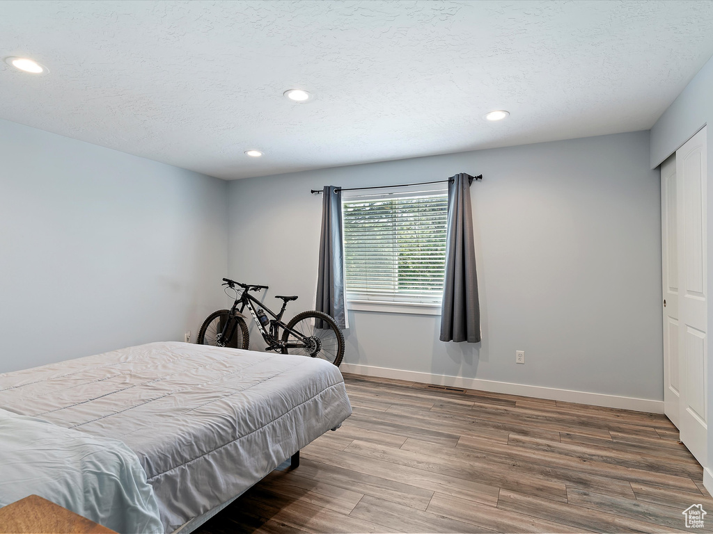 Bedroom with wood finished floors, recessed lighting, baseboards, and a textured ceiling