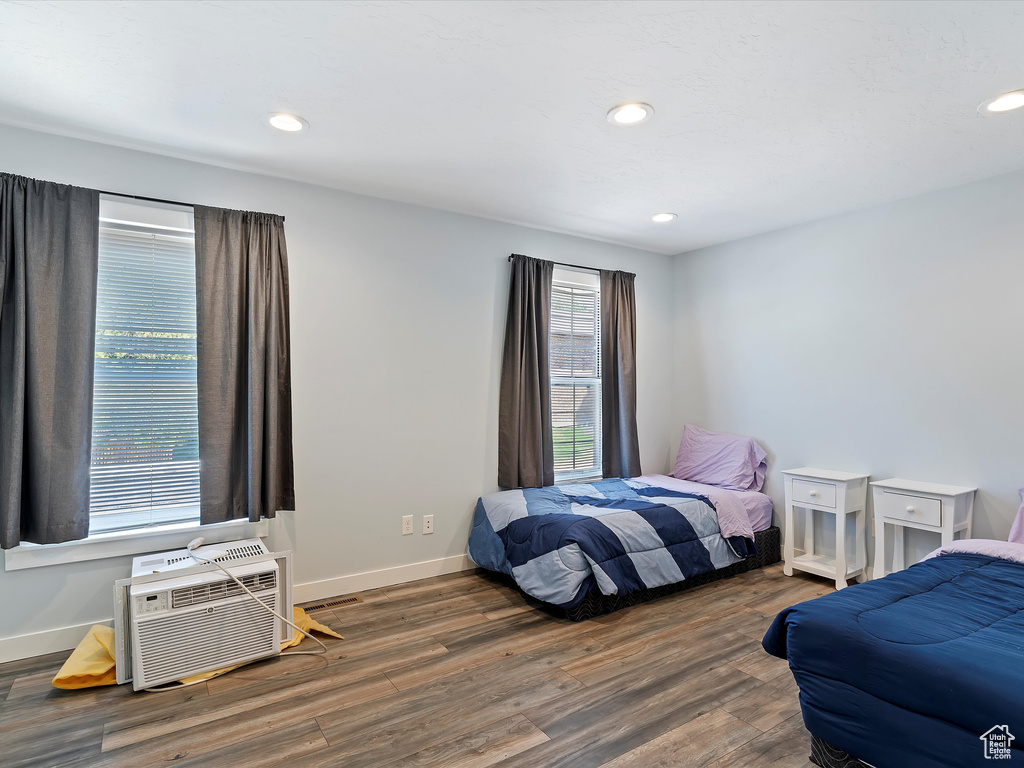 Bedroom featuring wood finished floors, baseboards, recessed lighting, and a wall mounted AC
