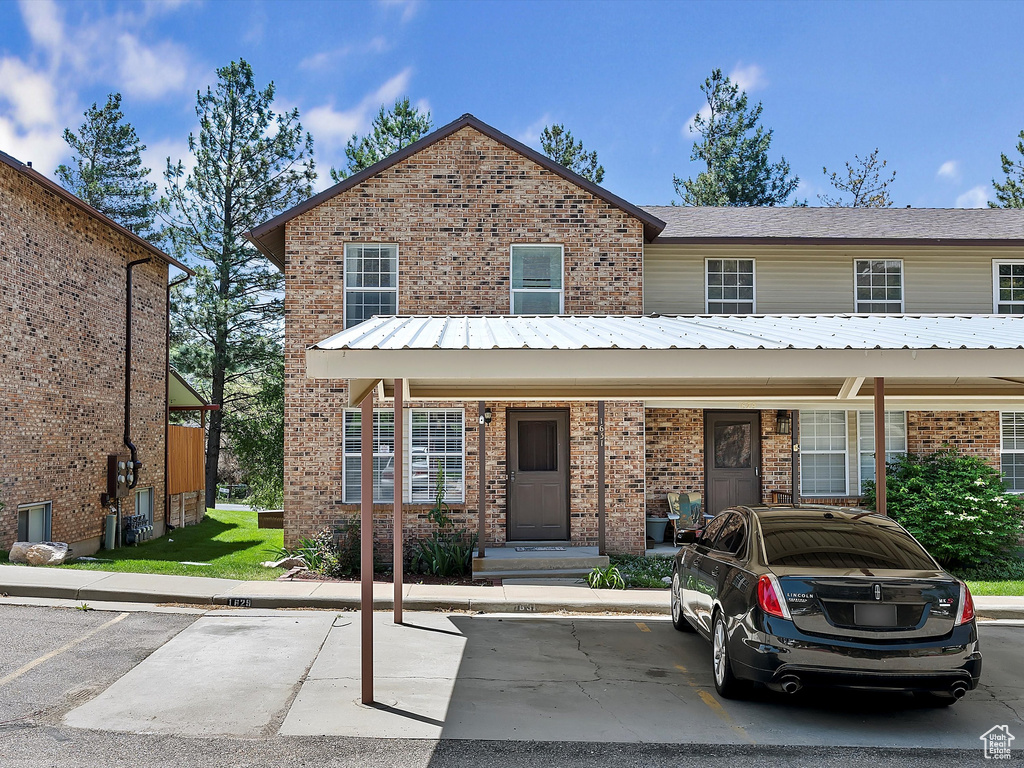 View of property with brick siding and uncovered parking
