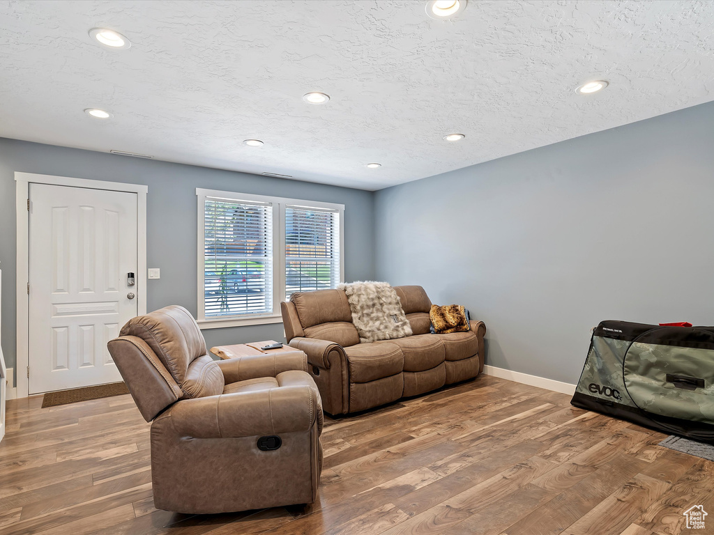 Living area with wood finished floors, recessed lighting, baseboards, and a textured ceiling
