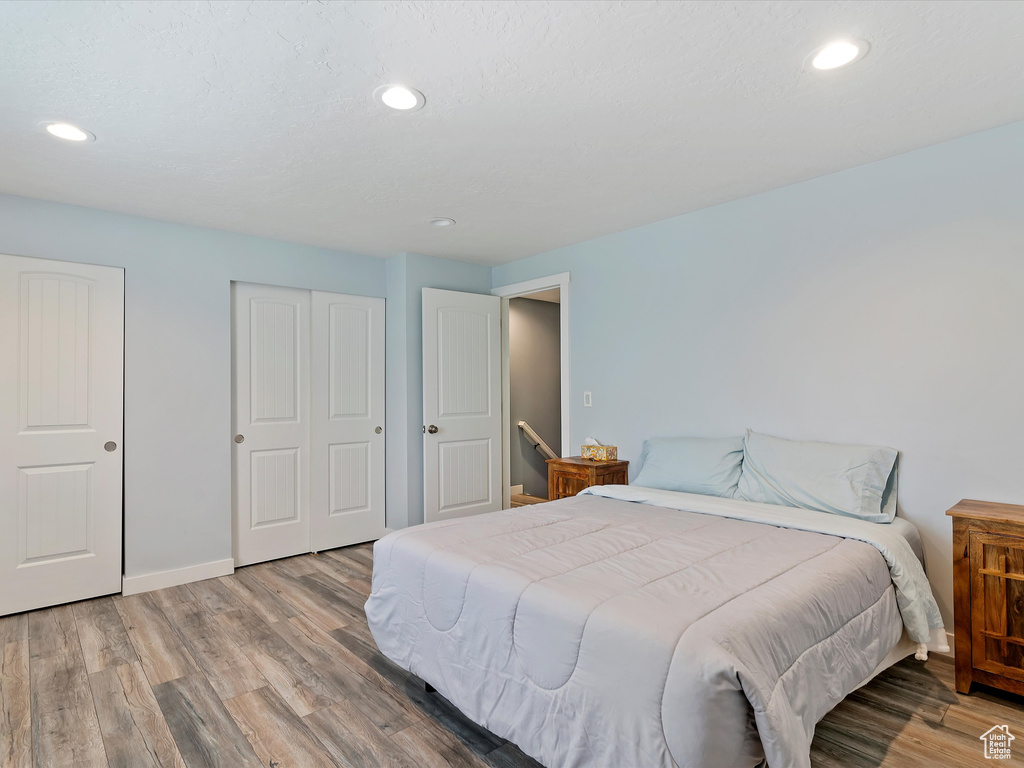 Bedroom featuring wood finished floors, baseboards, recessed lighting, and a closet