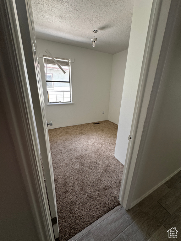 Carpeted empty room featuring a textured ceiling