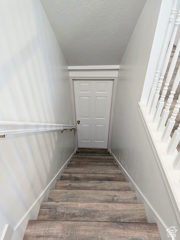Stairs featuring wood finished floors and a textured ceiling
