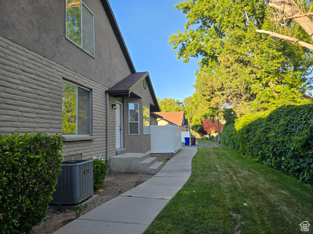 View of home\\\\\\\'s exterior featuring central AC unit, stucco siding, and a lawn