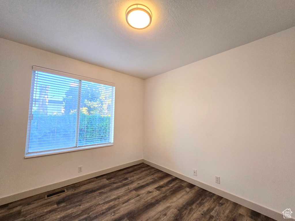 Empty room with dark wood-style floors and baseboards