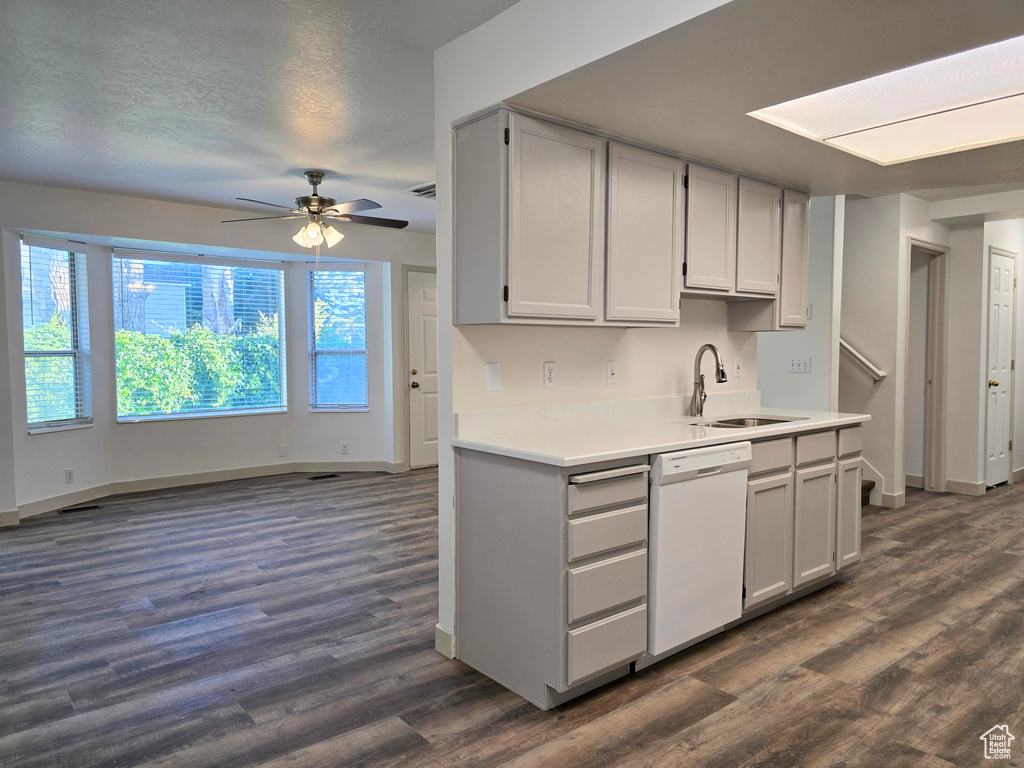Kitchen featuring a sink, dishwasher, dark wood-style floors, baseboards, and ceiling fan
