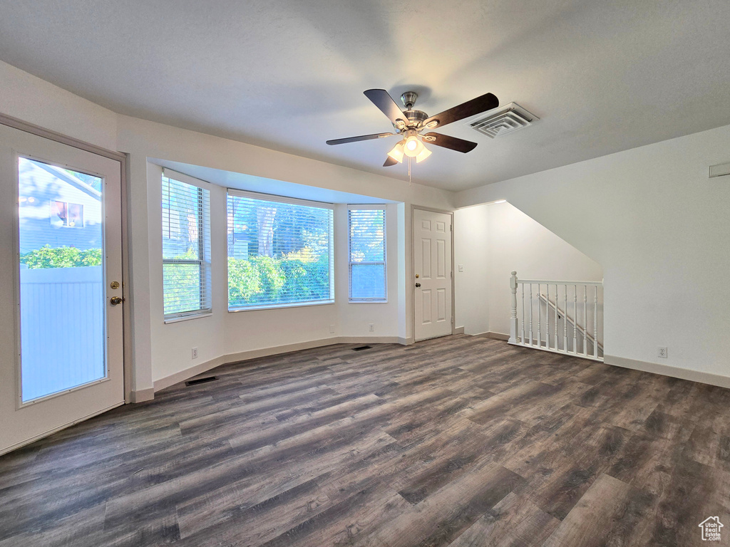 Unfurnished room featuring dark wood finished floors, baseboards, and ceiling fan