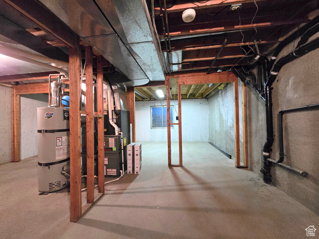 Unfinished basement featuring strapped water heater and heating unit