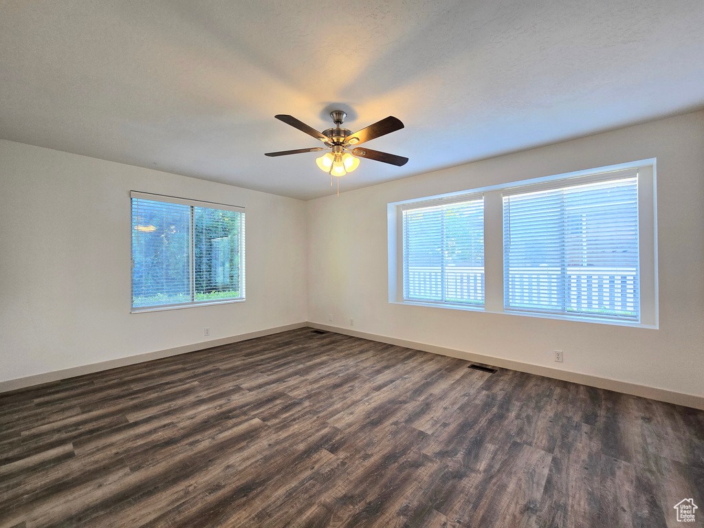 Spare room with dark wood-type flooring, baseboards, and a ceiling fan