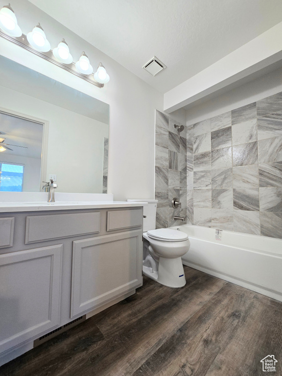 Full bathroom featuring toilet, vanity, bathtub / shower combination, wood finished floors, and ceiling fan