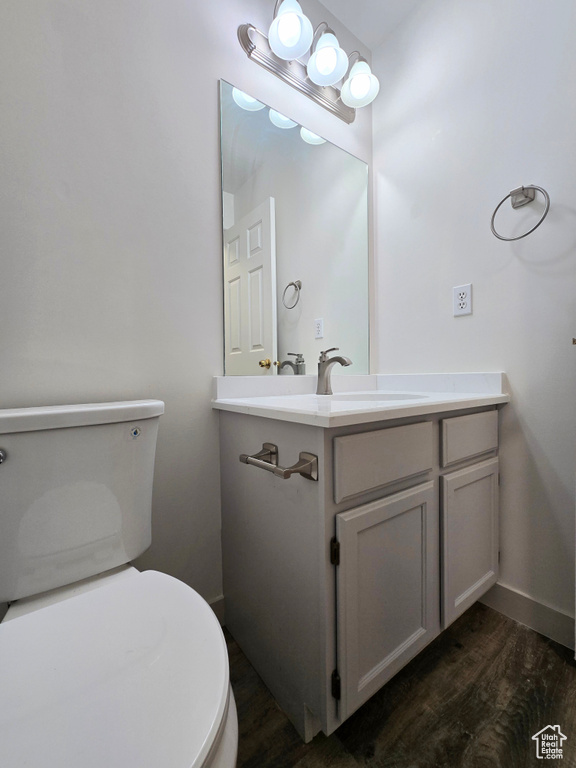 Bathroom featuring toilet, wood finished floors, vanity, and baseboards