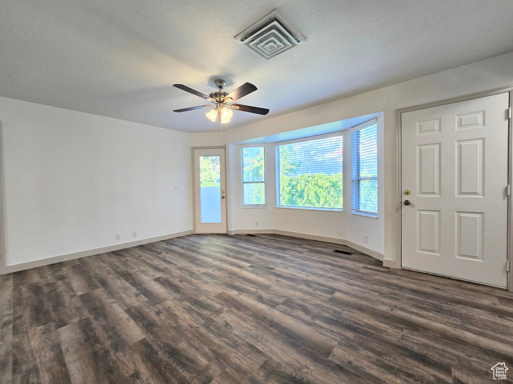 Unfurnished room with dark wood-style floors, baseboards, and ceiling fan