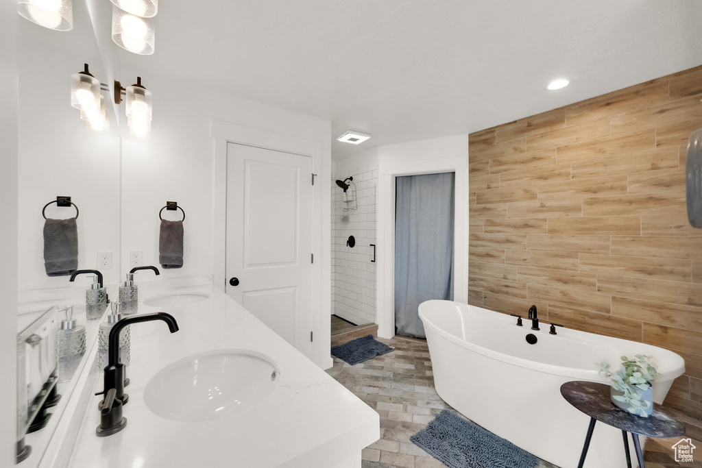 Full bath with a shower stall, double vanity, a freestanding tub, tile walls, and recessed lighting